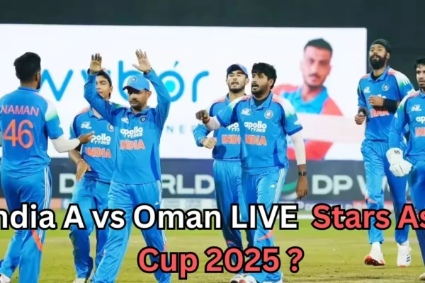 A group of India A cricket players wearing blue jerseys gather on the field during a match. One player has “NAMAN 46” on his back. The players appear to be celebrating or discussing a play. A large blurred screen with another player’s image is visible in the background. Text over the image reads: “India A vs Oman LIVE Stars Asia Cup 2025?