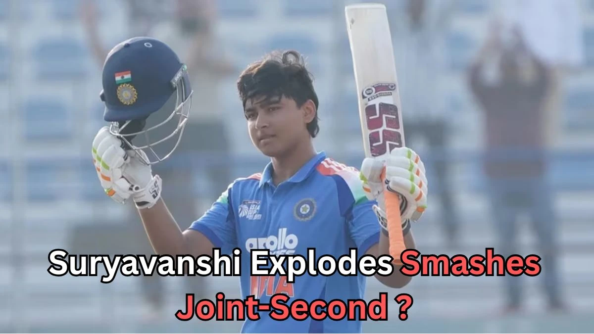 A young cricketer wearing an Indian team jersey raises his bat and helmet in celebration after a significant achievement. The player, likely a junior or emerging talent, smiles as he acknowledges the crowd. The background features empty seats in a stadium. Text at the bottom reads: "Suryavanshi Explodes Smashes Joint-Second?
