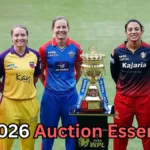 Six women cricketers from different WPL teams stand side by side on a cricket field, smiling and posing behind the Women’s Premier League trophy placed on a podium. They are wearing their respective team jerseys in colors like orange, yellow, blue, red, and light blue. Text at the bottom of the image reads: “WPL 2026 Auction Essentials?