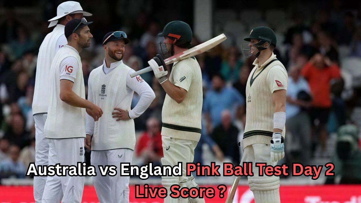 England fielders and two Australian batters stand together on the cricket field during the Ashes pink-ball Test, appearing to share a light moment, with text overlaid asking for the Australia vs England Pink Ball Test Day 2 live score.