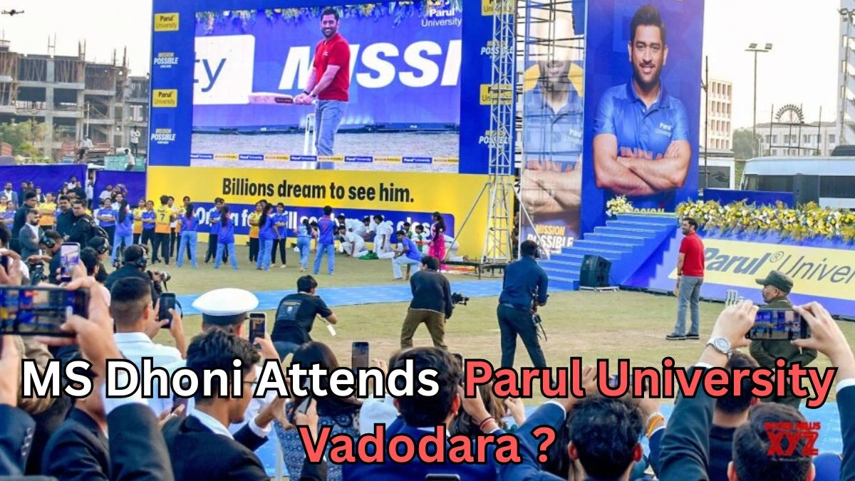 A large crowd gathers at an outdoor event where a well-known cricketer appears on stage at Parul University in Vadodara. Huge screens display his image, including one showing him holding a cricket bat and another showing him posing with folded arms. Many people in the audience are taking photos and videos. Text on the image reads: “MS Dhoni Attends Parul University Vadodara?