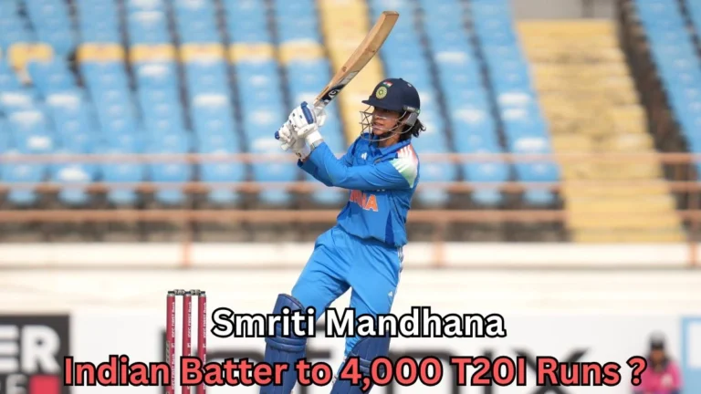 A female cricket player in India’s blue uniform swings her bat during a match, wearing a helmet and gloves, with empty blue stadium seats in the background and on-image text about reaching 4,000 T20I runs.