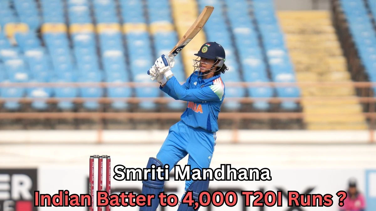 A female cricket player in India’s blue uniform swings her bat during a match, wearing a helmet and gloves, with empty blue stadium seats in the background and on-image text about reaching 4,000 T20I runs.