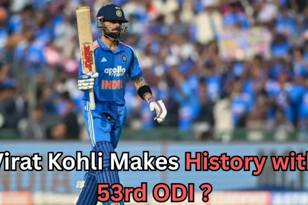 A cricketer from the Indian national team in a blue jersey is walking on the field holding his bat upright, with a large crowd of fans in the background. Bold text across the bottom of the image reads: “Virat Kohli Makes History with 53rd ODI?
